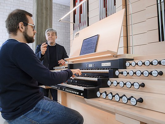 Unterrichtssitutation Kirchenmusik in einem Orgelraum mit Professor und einem Studierenden.