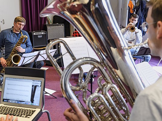 Unterrichtssituation Jazz/Pop mit Professor und zwei Studierenden mit verschiedenen Instrumenten.