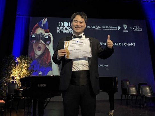 Person auf der Bühne mit einer Urkunde in der Hand