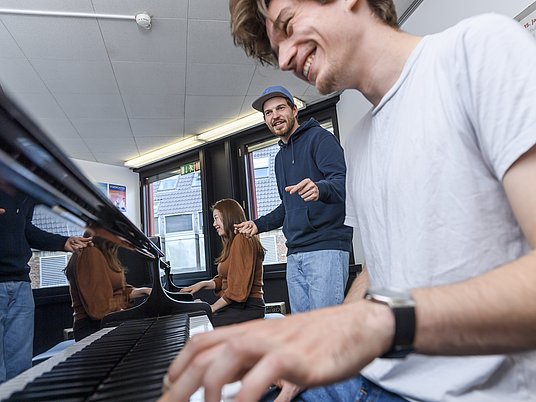 Unterrichtssituation mit einem Studierenden und Professor am Klavier.