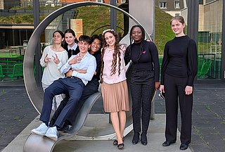 Gruppe junger Personen im und vor einem Kunstwerk