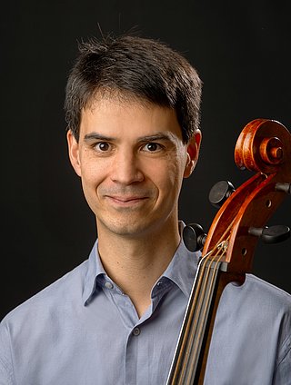 Es ist eine männliche Person im Portraitmodus zu sehen. Vor seiner Brust ist der Steg einer Viola da Gamba zu sehen.