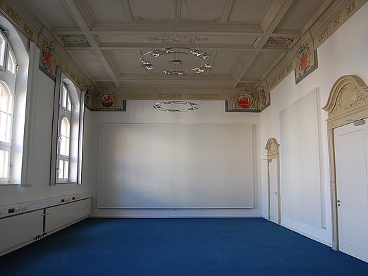 Kammermusiksaal am Standort Wuppertal mit blauen Teppich und Stuck an der Decke.