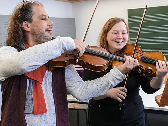 Zwei Personen spielen auf zwei Violinen