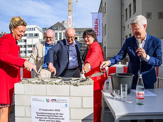 Fünf Personen mauern die Zeitkapsel des Neubaus am Standort Köln ein.