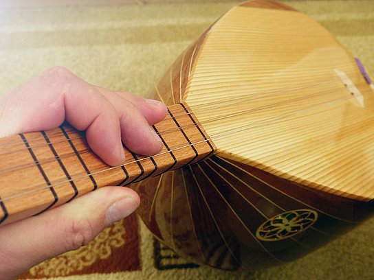 Eine Hand hält das Instrument Baglama fest