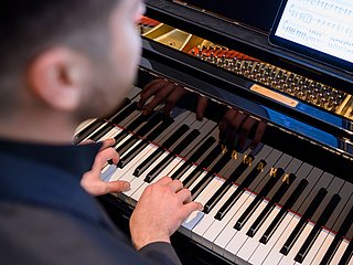 Ausschnitt einer Person die Klavier spielt.