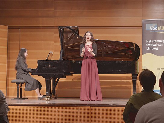 Zwei Personen auf der Bühne, eine Person singt und eine spielt Klavier