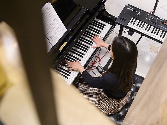 Studierende spielt Klavier und wird von oben fotografiert.