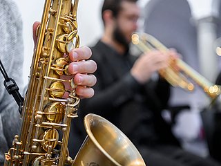 Studierende spielen Trompete und Saxophon.