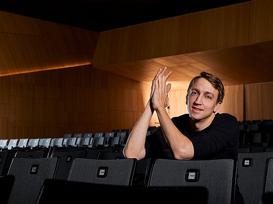 Person sitzt in einer Stuhlreihe