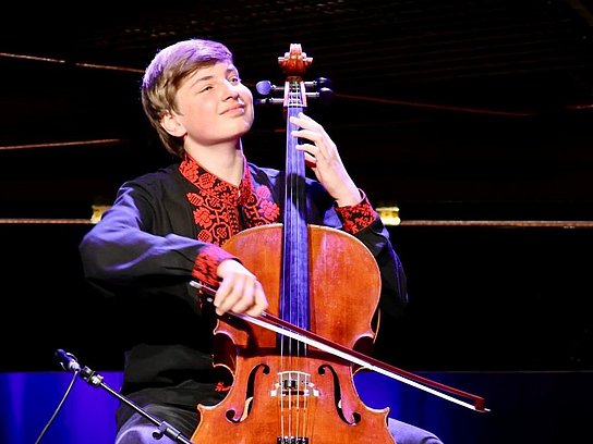 Person mit einem Violoncello auf der Bühne