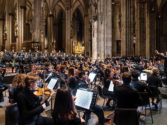 Orchester und Dirigent vor Publikum im Kölner Dom.