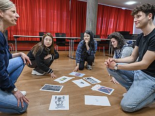 Studierende sitzen im Kreis und diskutieren miteinander