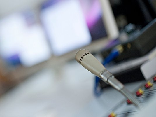 Mikrofon vor unscharfen Hintergrund mit mehreren Computern.