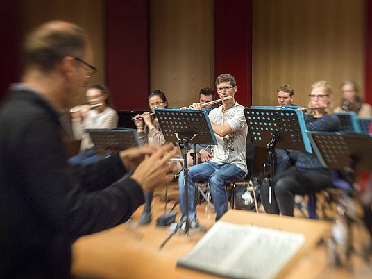 Ensemble auf der Bühne mit einem Dirigenten.