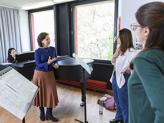 Professorin mit zwei Studierenden beim Gesangsunterricht.