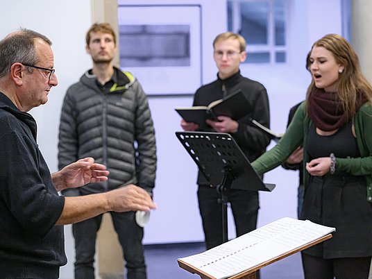 Professor mit drei Studierenden beim Gesangsunterricht.