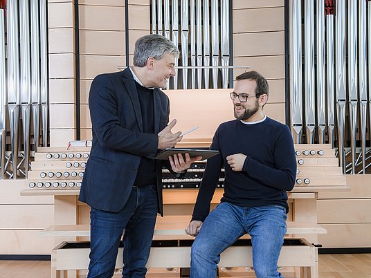 Unterrichtssitutation Kirchenmusik in einem Orgelraum mit Professor und einem Studierenden.