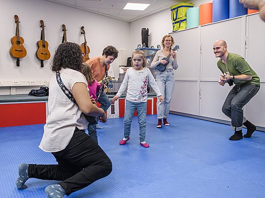 Unterrichtssituation Elementare Musikpädagogik mit Professorin, Studierenden und Kindern.