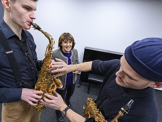 Unterrichtssituation Saxophonspieler*in wird bei der Fingerhaltung korrigiert
