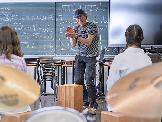 Unterrichtssituation Elementare Musikpädagogik mit zwei Kindern und Professor.