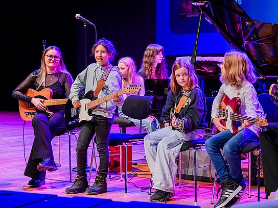 Kinder auf der Bühne die Gitarre spielen