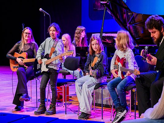 Kinder auf der Bühne die Gitarre spielen