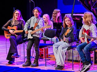 Kinder auf der Bühne die Gitarre spielen