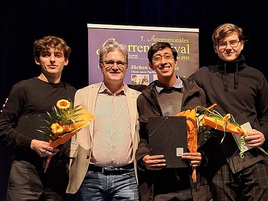 Vier Personen bei der Preisverleihung mit Blumen und Urkundenmappe