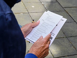 Person hält einen Flyer in den Händen.