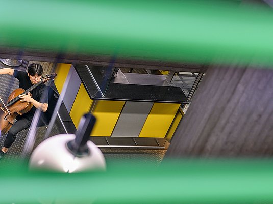 Cellist*in im Foyer der Hochschule am Standort Köln