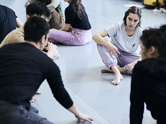 Gruppe Tanzstudierende die auf den Boden sitzen.