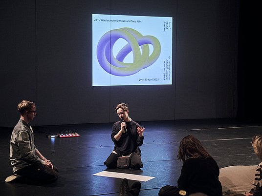 Gruppe Studierende auf dem Tanzboden und im Hintergrund ist das Relay-Logo abgebildet.